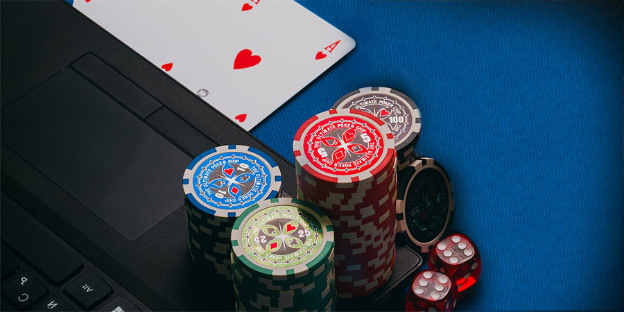 playing cards, dice, casino chips on top of a laptop computer and casino table